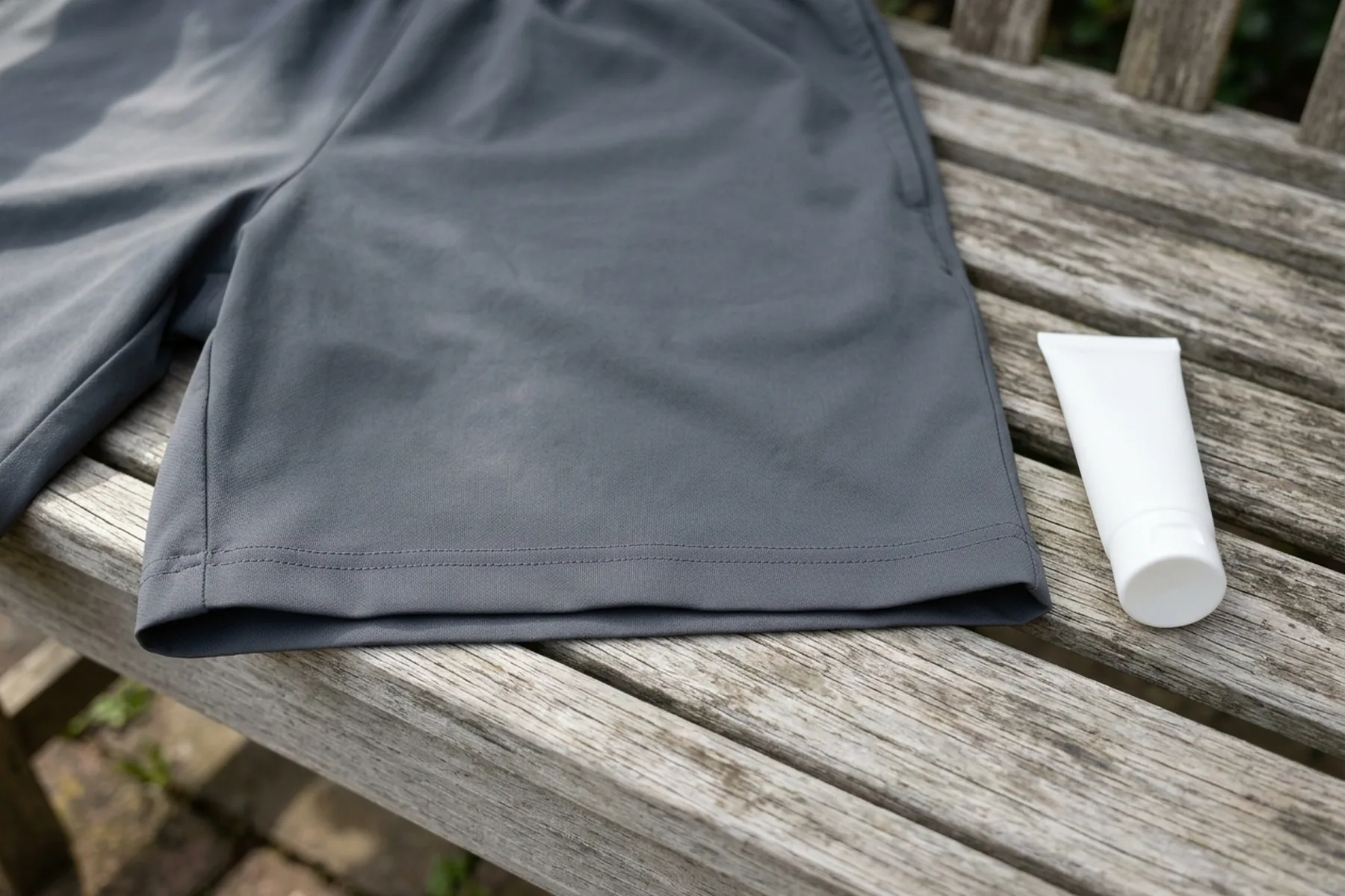 Grey athletic shorts hem laid flat beside a closed plain white tube